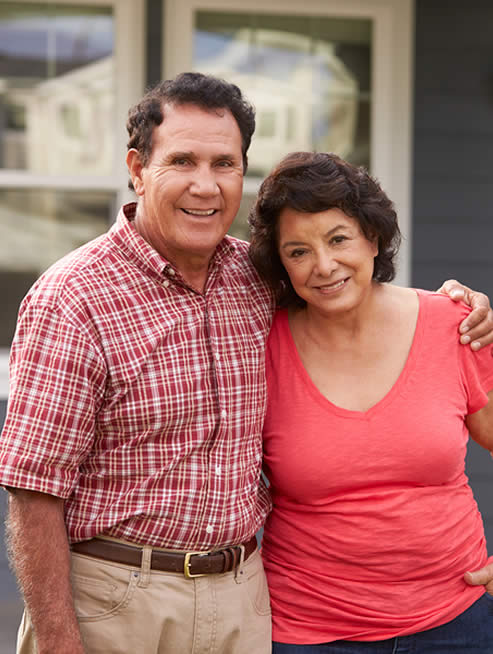 Senior couple in front of their home.